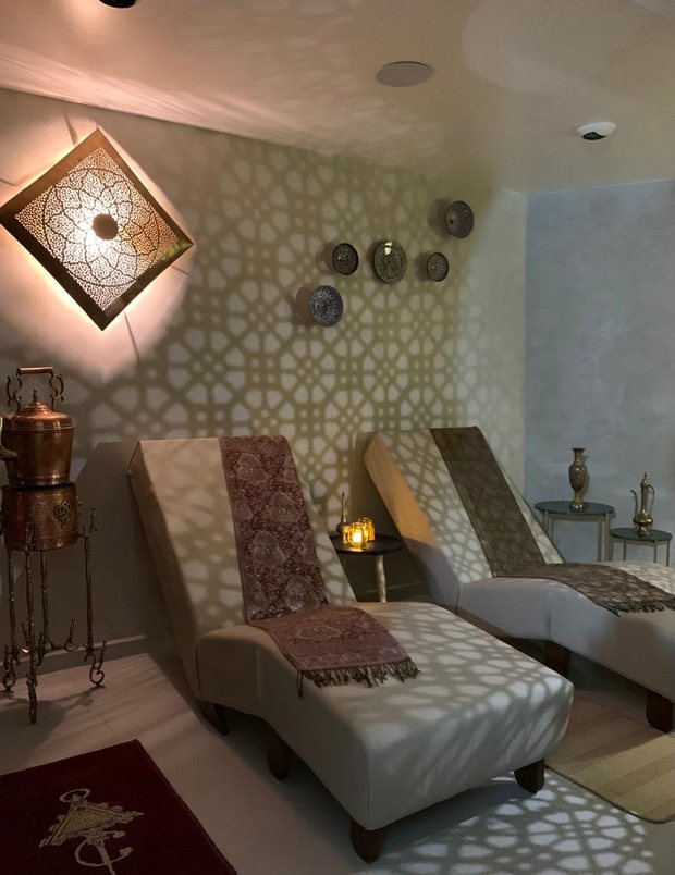 La salle de repos : transats habillés de jetés, applique ajourée projetant des ombres géométriques, urne de hammam en cuivre
